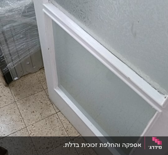 דלת זכוכית עם ידית מתכת על רצפת קרמיקה